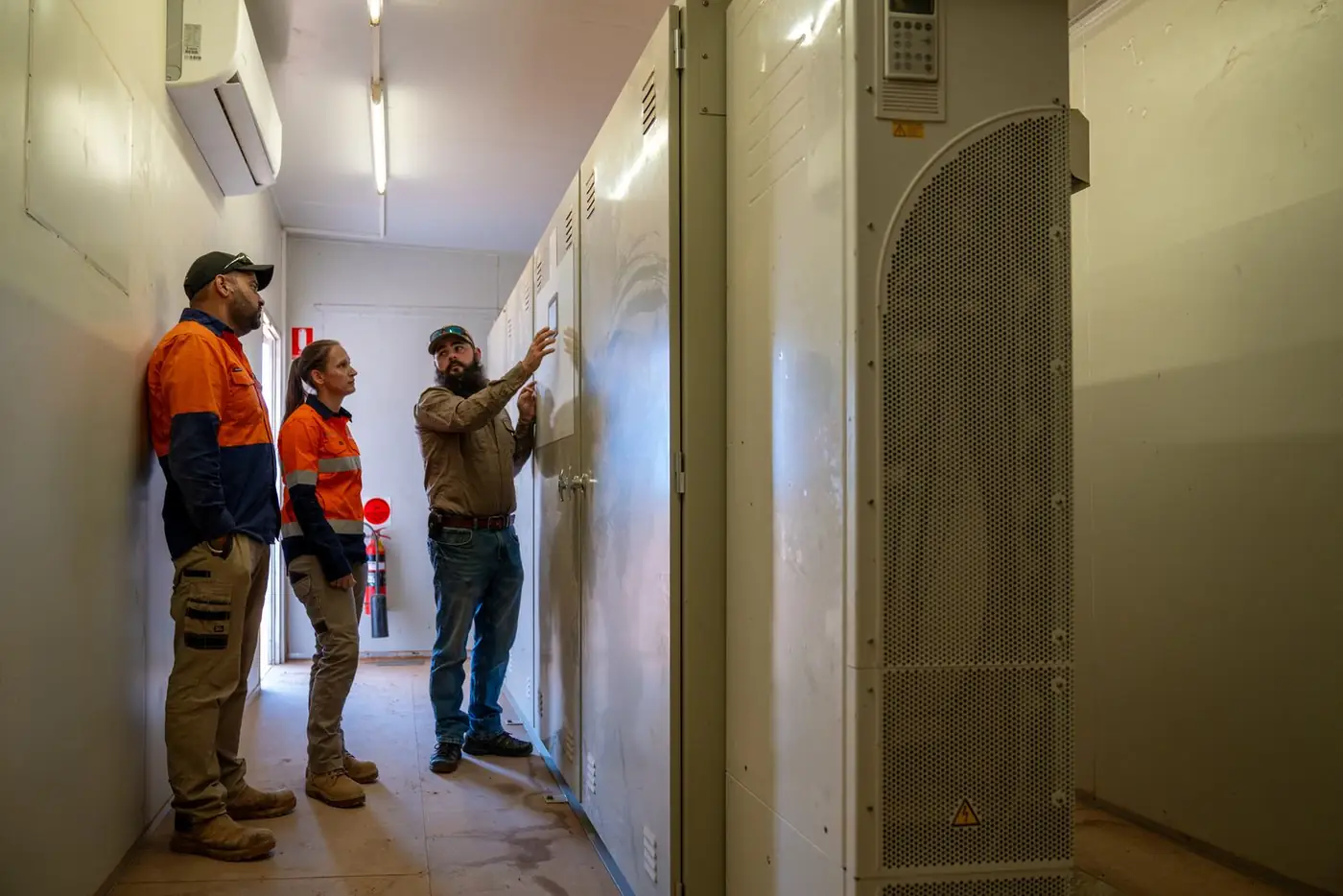 Three Ardal staff checking switchboards in a pump station control room