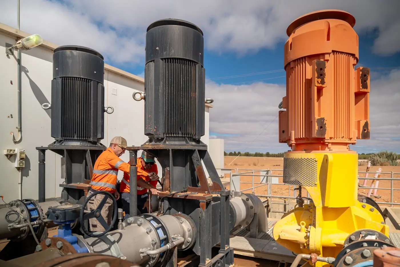 Ardal technicians working between large pump motors at a pump station