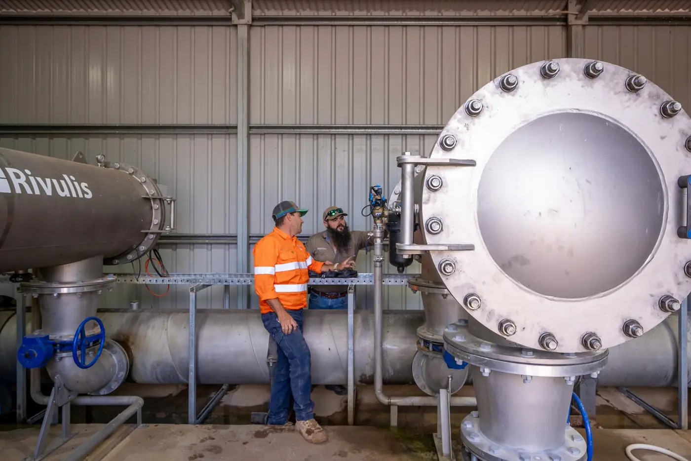 Two Ardal technicians working among large filters in a pump shed