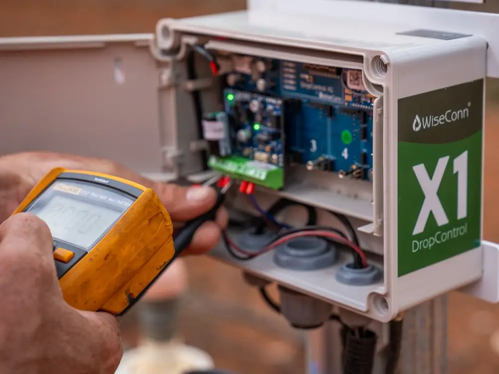 Ardal technician testing a WiseConn X1 controller with a multimeter