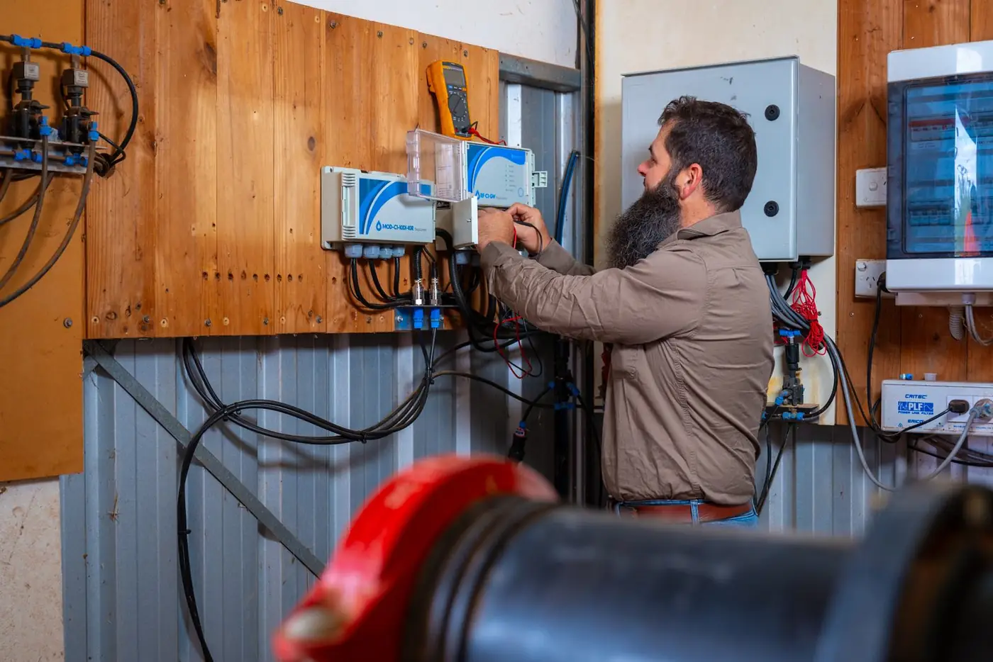 Ardal technician working on irrigation controllers on a pump shed wall