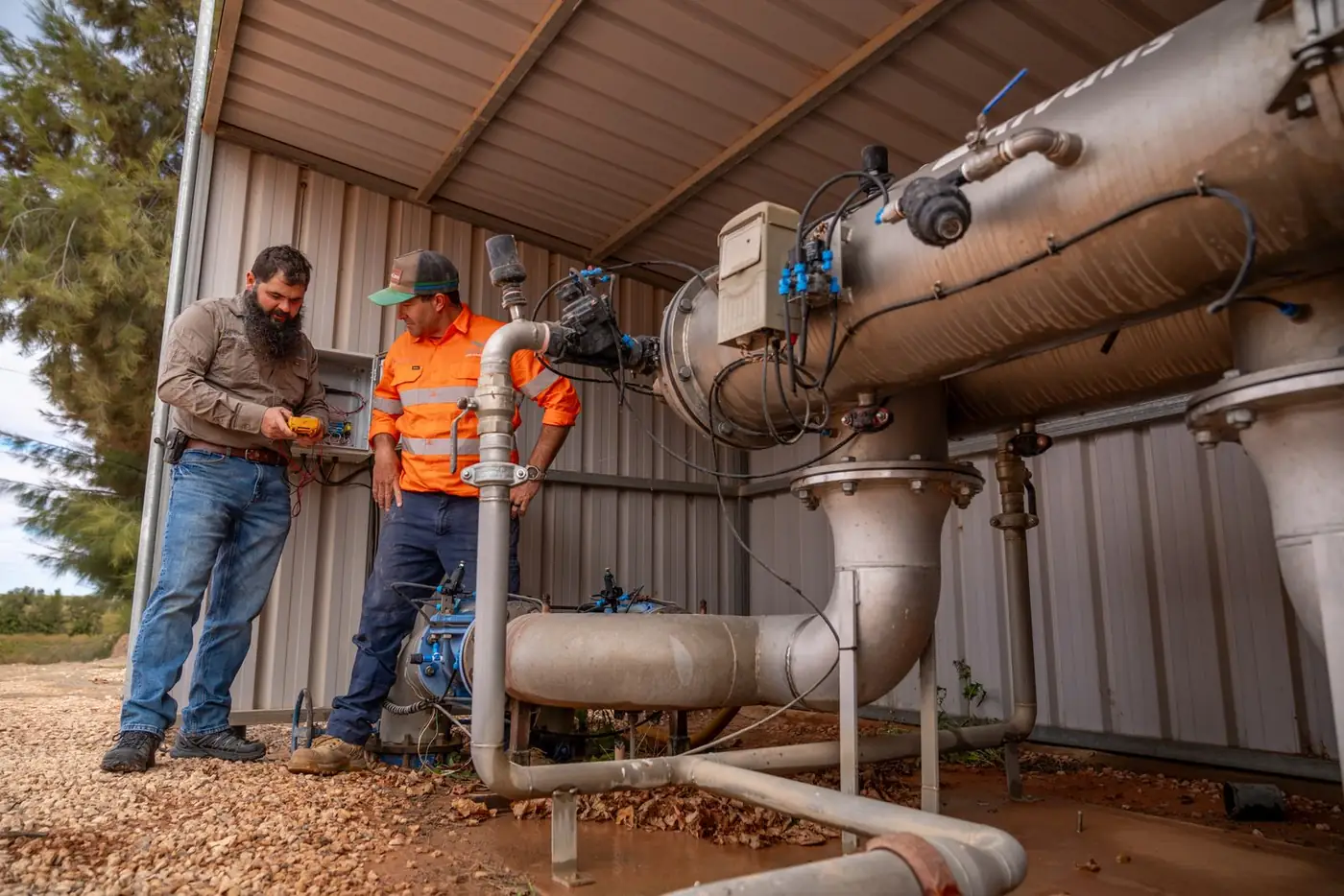 Two Ardal technicians checking a filtration station in a pump shed