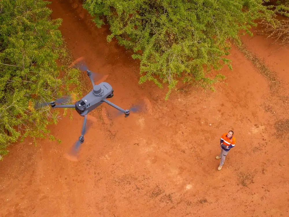 Ardal drone flying low over almond trees with the pilot visible below