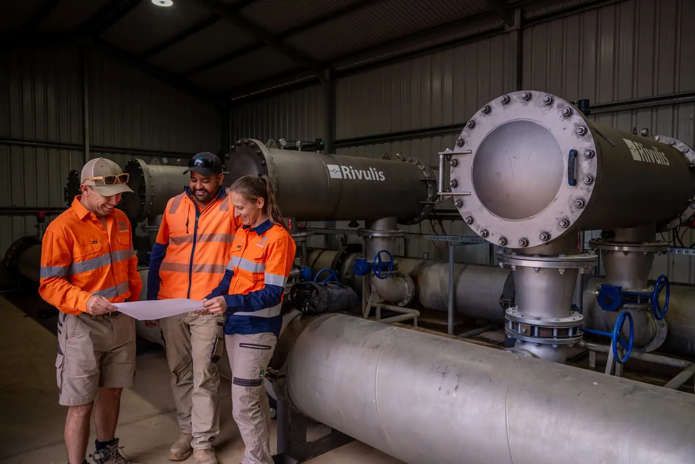 Three Ardal staff in hi-vis reviewing a plan beside a filtration unit