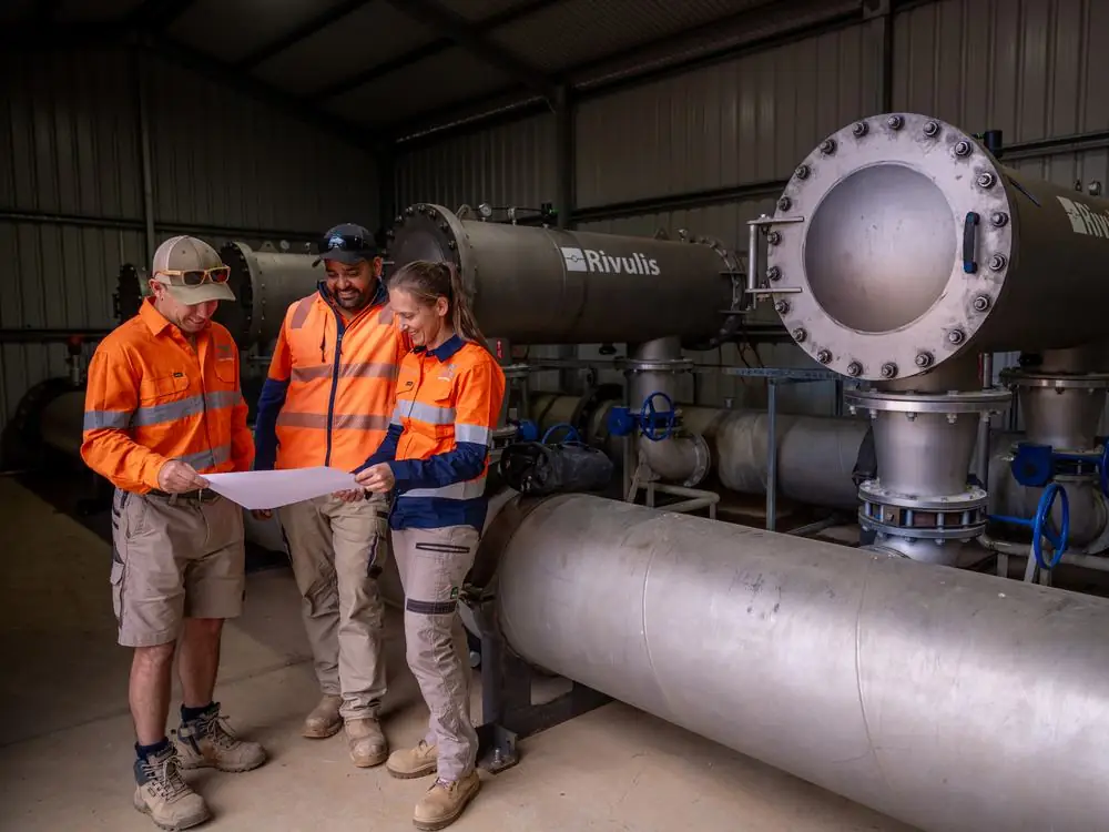 Three Ardal staff reviewing a plan in a pump shed