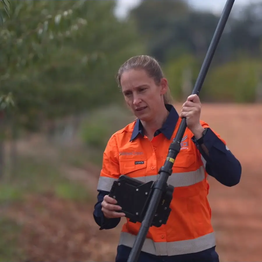Surveyor with an RTK GPS pole and controller in an orchard, from Ardal's surveying video